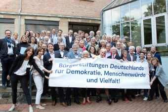 Bürgerstiftungsakteure versammeln sich hinter einem Transparent mit der Aufschrift "Bürgerstiftungen Deutschlands für Demokratie, Menschenwürde und Vielfalt".