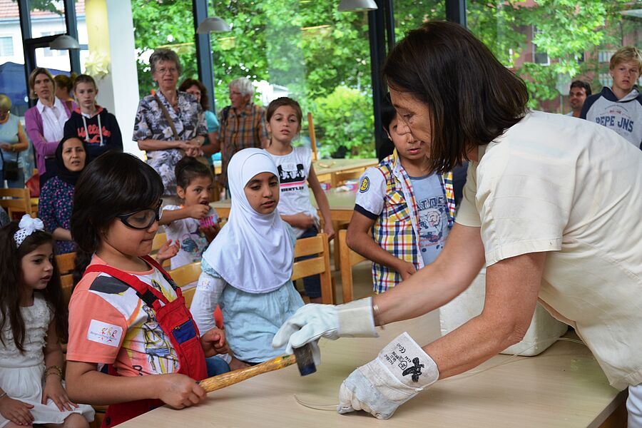 Eine Frau zeigt einer Gruppe von Kindern physikalische Experimente.